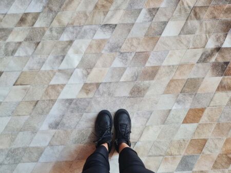 Top view of LIME Ombre Taupe Patchwork Cowhide Rug with feet Top view of LIME Ombre Taupe Patchwork Cowhide Rug with feet showing for scale comparison