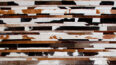 White, brown and black patchwork cowhide rug designed in stripes