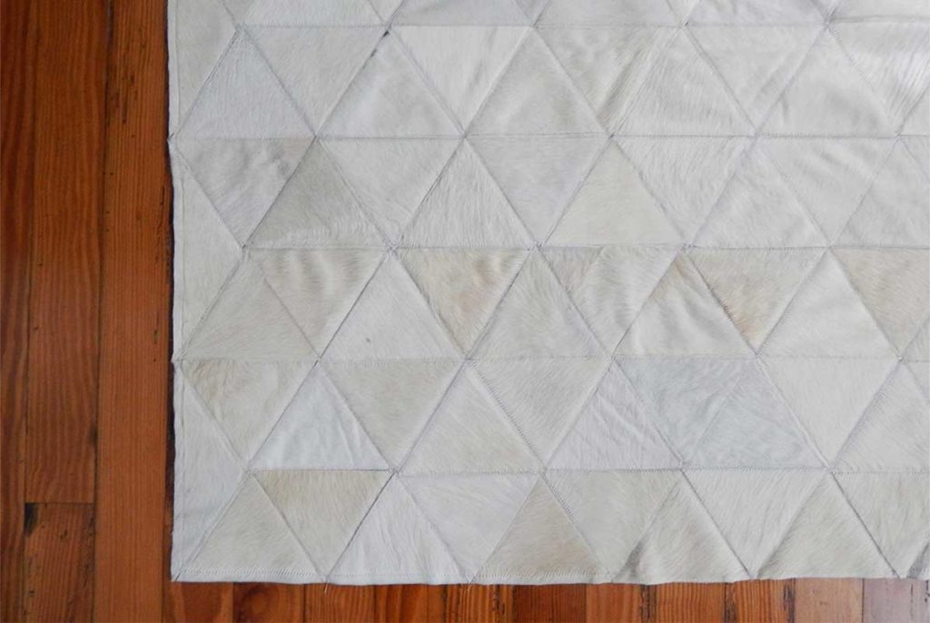 White patchwork cowhide rug, wooden floor