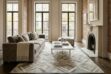 New York brownstone style apartment with gray couch, fireplace and a diamond taupe cow hide rug anchoring the whole space.