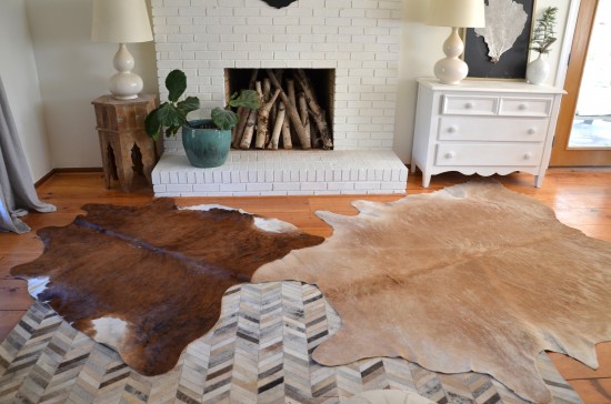 Chevron Style leather area rug combined with two cowhides in different tones of brown and tan, with a fireplace and cactus