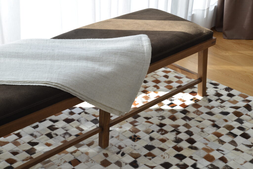 Mini Squares patchwork cowhide rug in white and browns, with a brown and wooden bench