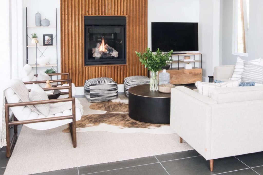 Modern style white area rug with a brown brindle cowhide, natural tones, wooden fireplace and round coffe table