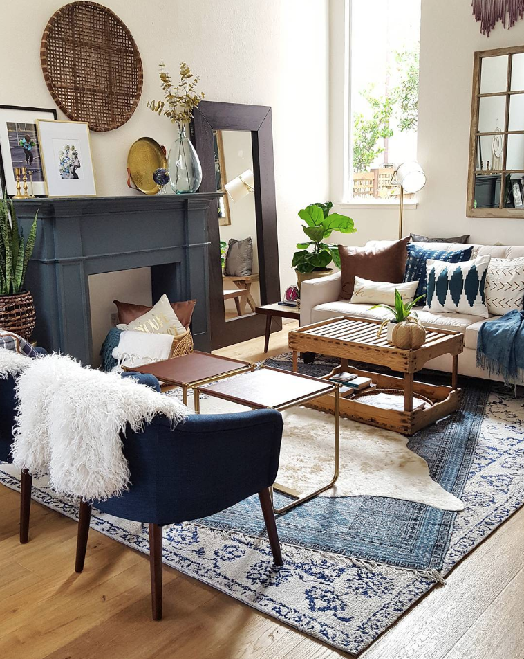 Many layers of cowhide rug, vintage and silk rug in a classy living room