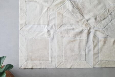 White Cube Cowhide Rug in big Patches, on gray floor White Cube Cowhide Rug in big Patches, on gray floor with plant
