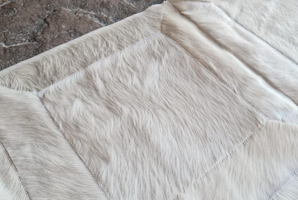 Hair view of a White Hide Patch Cowhide Rug on stone