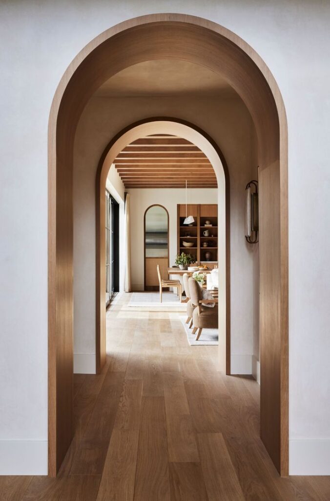 arched passageways leading to a modern wooden living room with exposed beams