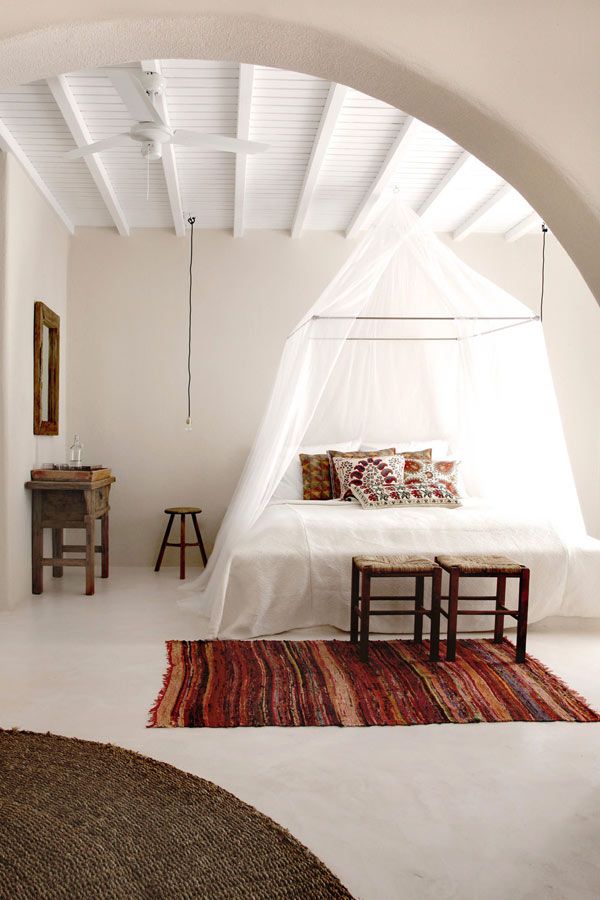 bedroom with arched entrance and soft lighting, Moroccan rug and bed hanging translucent fabric