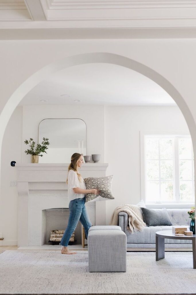 arched division between entrance and soft toned living room in white an baby blue