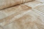 Detail of Beige Mona patchwork cowhide rug showing stitched cowhide squares and texture