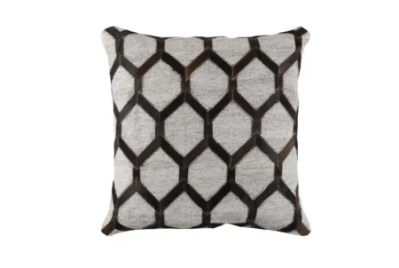 04 Mixed cowhide fabric pillow in gry and brown A single, isolated, square throw cushion featuring a precise repeating geometric pattern. The pattern is composed of alternating panels: light gray textured fabric and pieces of dark brown cowhide with a visible hair texture, forming a stylized hexagonal or lattice design. Detailed stitching runs along the border, and the item is presented on a plain white background.