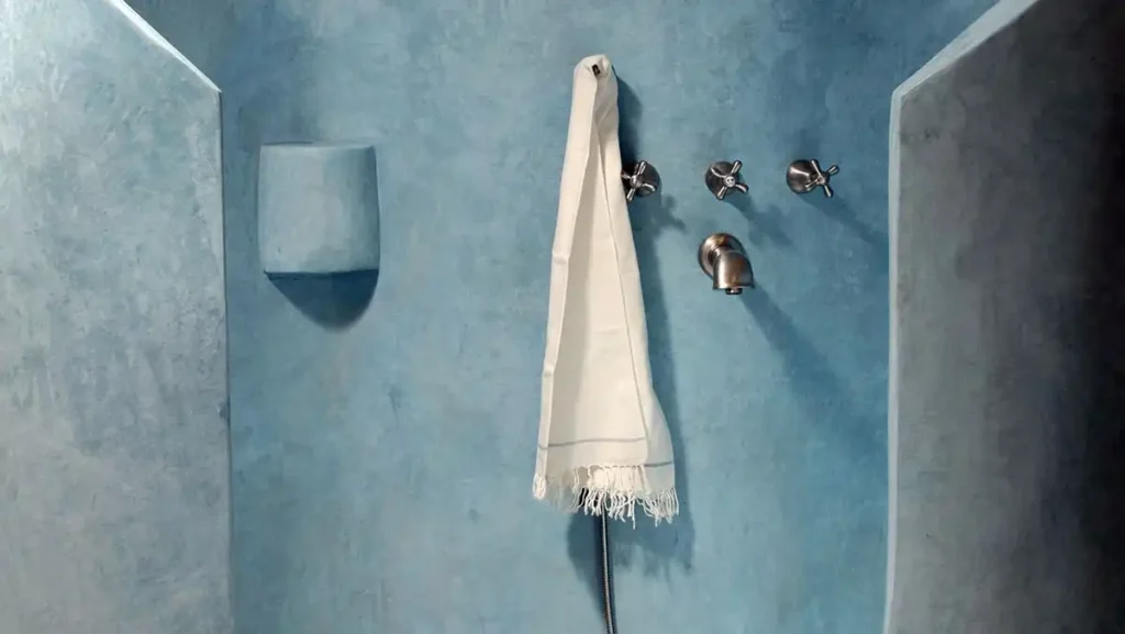 Close-up of tadelakt lime plaster wall finish with a soft, hand-burnished texture in a soft blue tone.